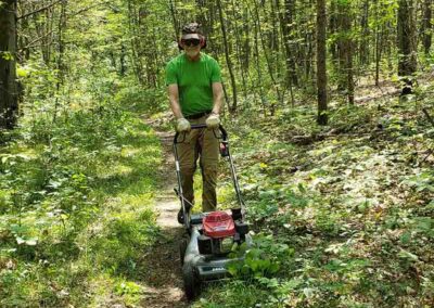 Green Durham Association - Image of Trail Volunteer mowing trail grass.